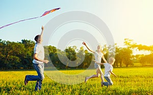 Dad, mom and son child flying a kite in summer nature photo