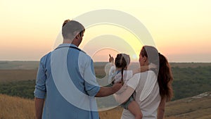 Dad, Mom is walking with her daughter showing child sunset. Happy family, mother, father and daughter are walking in the