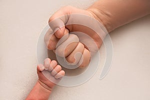 Dad and newborn boy son keep their hands in a fist, small and big fists. Father and son, the first boxing punch.