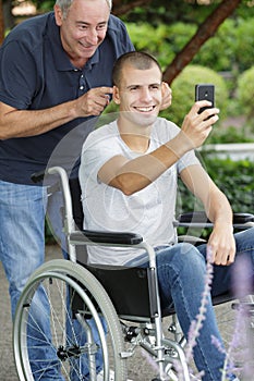 dad playfully holding handicapped sons ears back for selfie