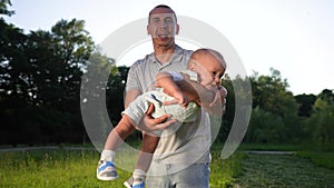 Dad playing with son baby in the park. Happy family kid dream concept. Dad shakes baby son in his arms play have fun in