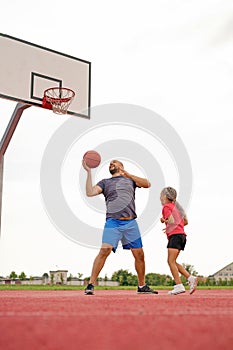 Dad plays basketball with a child, throwing a ball into the basket