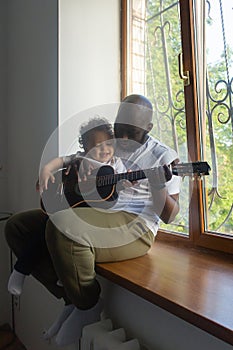 Dad plays guitar to son song, Afro Amercans