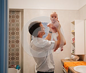 dad plays with newborn son and tosses him up in the bathroom. water procedures