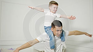 Dad plays with son sitted on his shoulders depicting a plane.