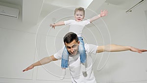 Dad plays with son sitted on his shoulders depicting a plane.