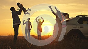 Dad plays and throws a joyful daughter into sky, mom and children dance at sunset. parents and children stopped for