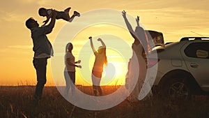 Dad plays and throws a joyful daughter into sky, mom and children dance at sunset. parents and children stopped for