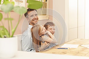 Dad, pre-teen boy and young girl laughing during homeschooling due to the coronavirus lockdown.