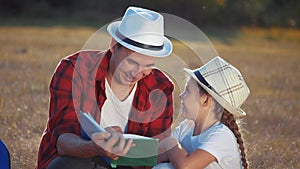 dad is reading a book to his daughter in the park on vacation. happy family kid dream concept. father reads a book to