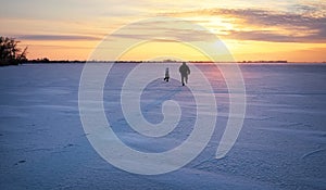 Dad is running for her daughter on a frozen river at sunset.