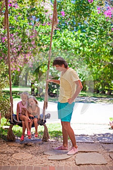 Dad shakes his young daughters on a swing in