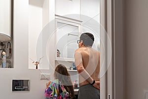 Dad is shaving beard in the bathroom with child girl, modern fatherhood, real life family moments