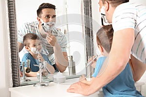 Dad shaving and little son imitating him photo