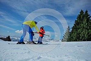 Dad show child how to ski going downhill holding poles in hands