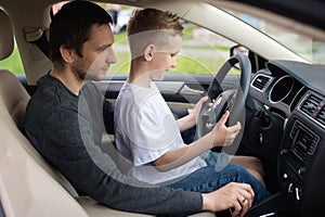 Dad shows his little son how to drive a car