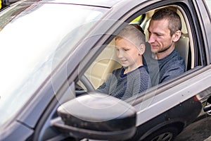 Dad shows his little son how to drive a car