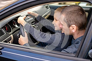 Dad shows his little son how to drive a car