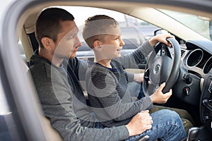 Dad shows his little son how to drive a car