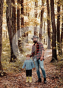 Dad and son in the autumn park play laughing. Happy family, father and baby son playing and laughing on autumn walk