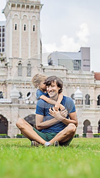 Dad and son on background of Merdeka square and Sultan Abdul Samad Building. Traveling with children concept VERTICAL