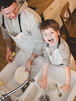 Dad and son doing the washing up in kitchen