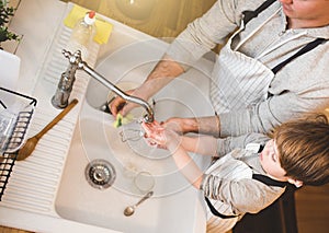 Dad and son doing the washing up in kitchen