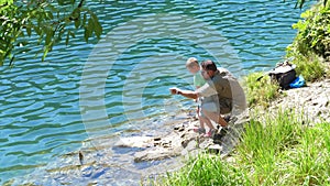 Dad and son fish a trout in a mountain lake. Concept of relax and healthy family outdoor life