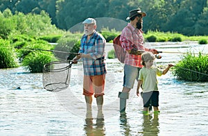 Dad and son fishing at lake. Grandfather, father and grandson fishing together. Grandson with father and grandfather