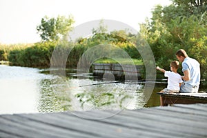 Dad and son fishing together on sunny day