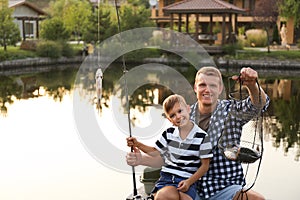 Dad and son fishing together on sunny day