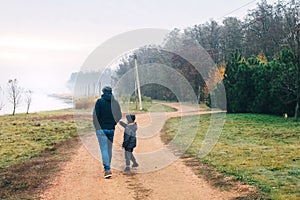Dad and son in forest. Family vacation among the autumn trees. Walk along a dirt road near the forest and a country house. The
