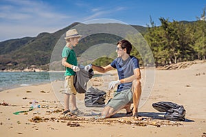 Dad and son in gloves cleaning up the beach pick up plastic bags that pollute sea. Natural education of children photo