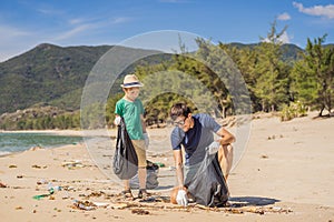Dad and son in gloves cleaning up the beach pick up plastic bags that pollute sea. Natural education of children