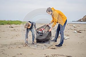 Dad and son in gloves cleaning up the beach pick up plastic bags that pollute sea. Natural education of children
