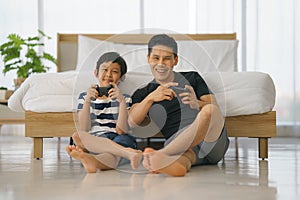 Dad and son have goodtime playing vdo game together in bedroom at home photo