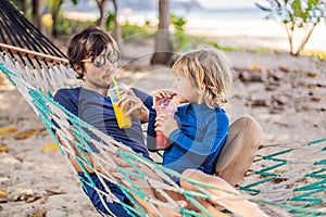 Dad and son having fun in a hammock with a drinks