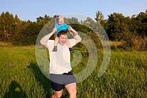 Dad and son having fun in nature in summer, father holding his child on his shoulders with pinwheel