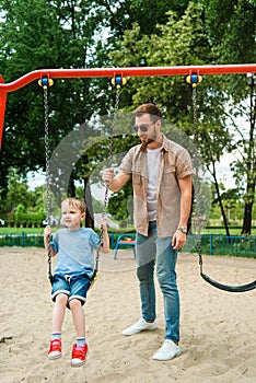 dad and son having fun on swing at playground