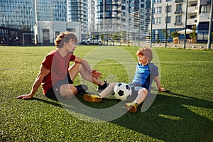 Dad and son having nice conversation after football training recreation activity