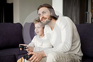 Dad and son holding joysticks enjoying playing video game togeth