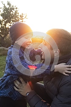 Dad and son hug and indulge in nature. The sun`s rays pass through the faces creating a feeling of warmth and affection. Loving