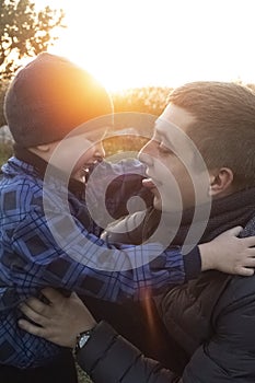 Dad and son hug and indulge in nature. The sun`s rays pass through the faces creating a feeling of warmth and affection. Loving