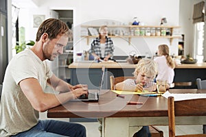 Dad and son at kitchen table, mum and daughter in background