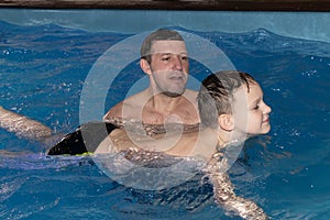 A Dad and son learn to swim in the pool