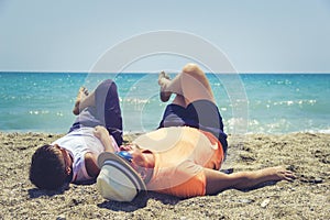 Dad and son lies and relaxing on the beach.