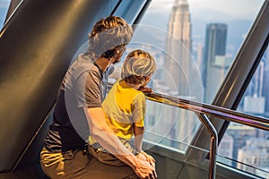 Dad and son are looking at Kuala lumpur cityscape. Panoramic view of Kuala Lumpur city skyline evening at sunset