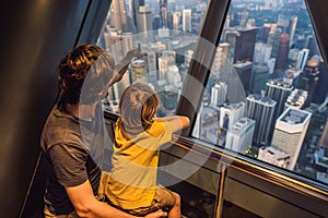 Dad and son are looking at Kuala lumpur cityscape. Panoramic view of Kuala Lumpur city skyline evening at sunset