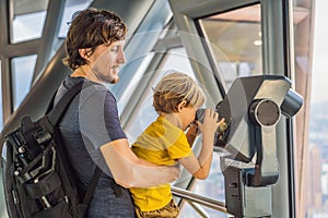 Dad and son are looking at Kuala lumpur cityscape. Use binoculars. Panoramic view of Kuala Lumpur city skyline evening