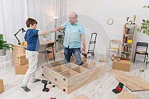 Dad and son make a turtle gesture while assembling furniture.